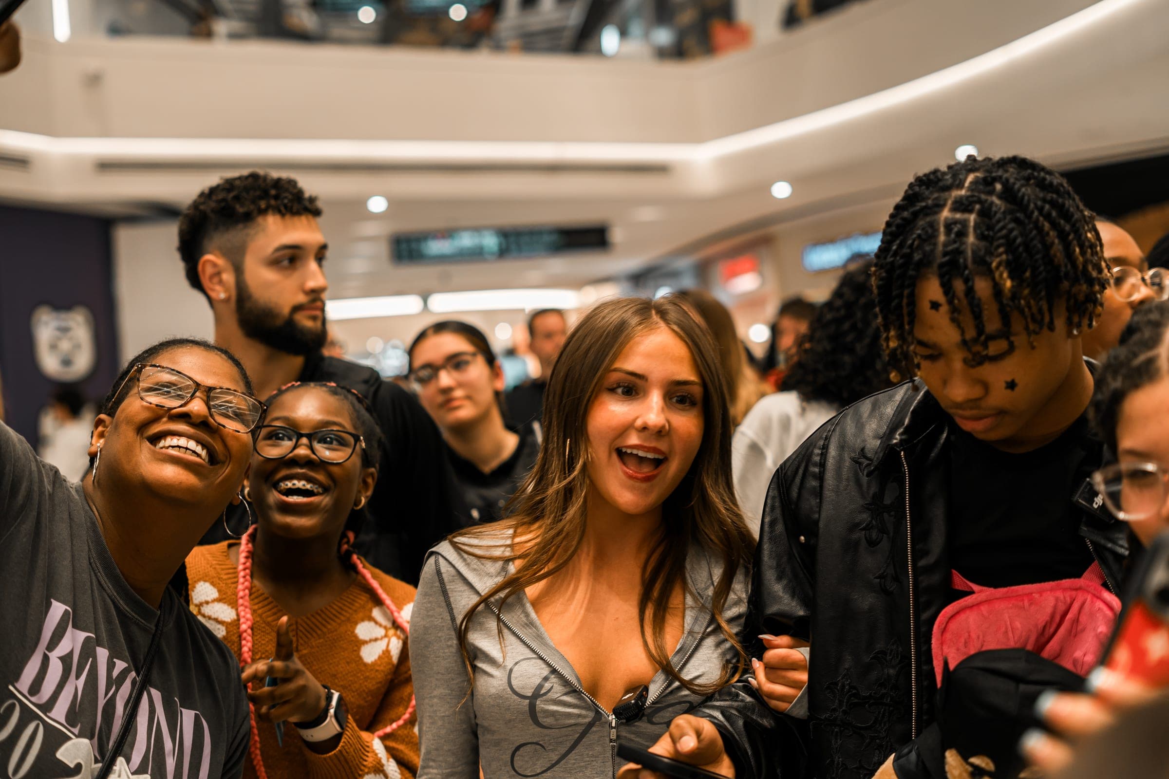Fans laughing as a creator walks past in a crowded mall