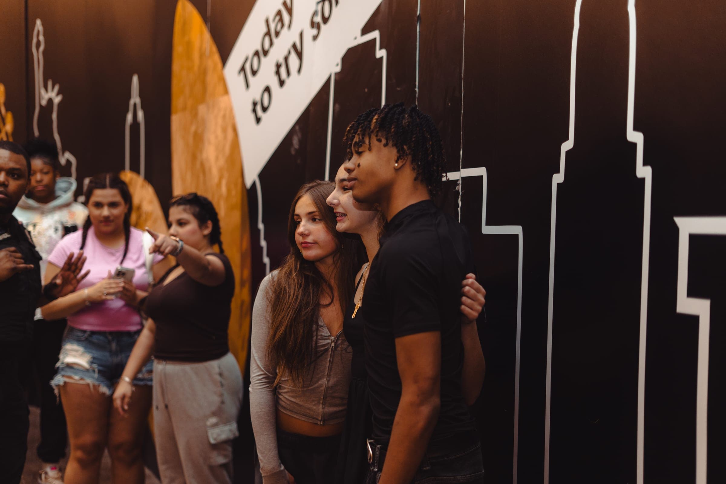 Creator posing with fans in front of a skyline mural