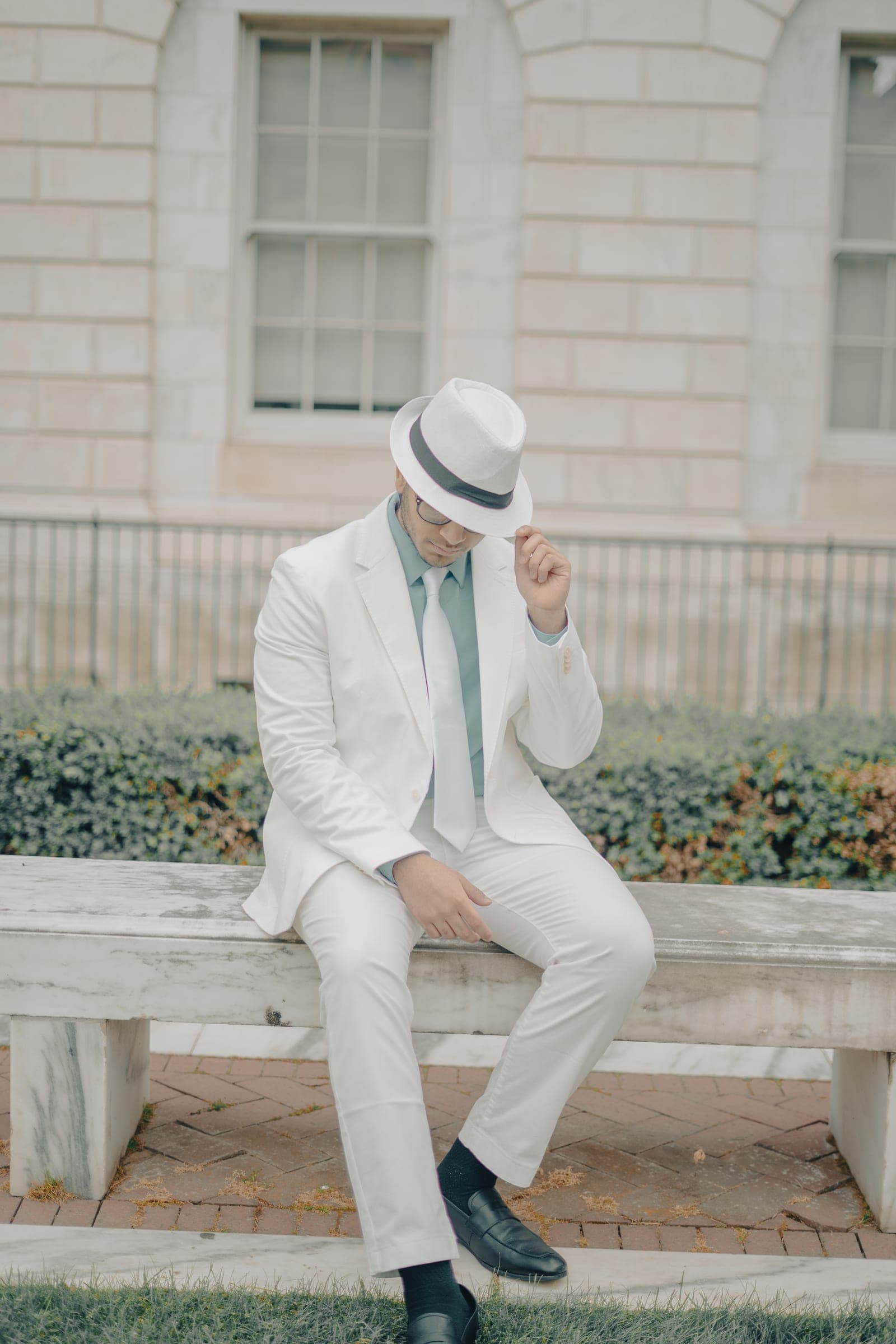Man in a white suit seated on a stone bench