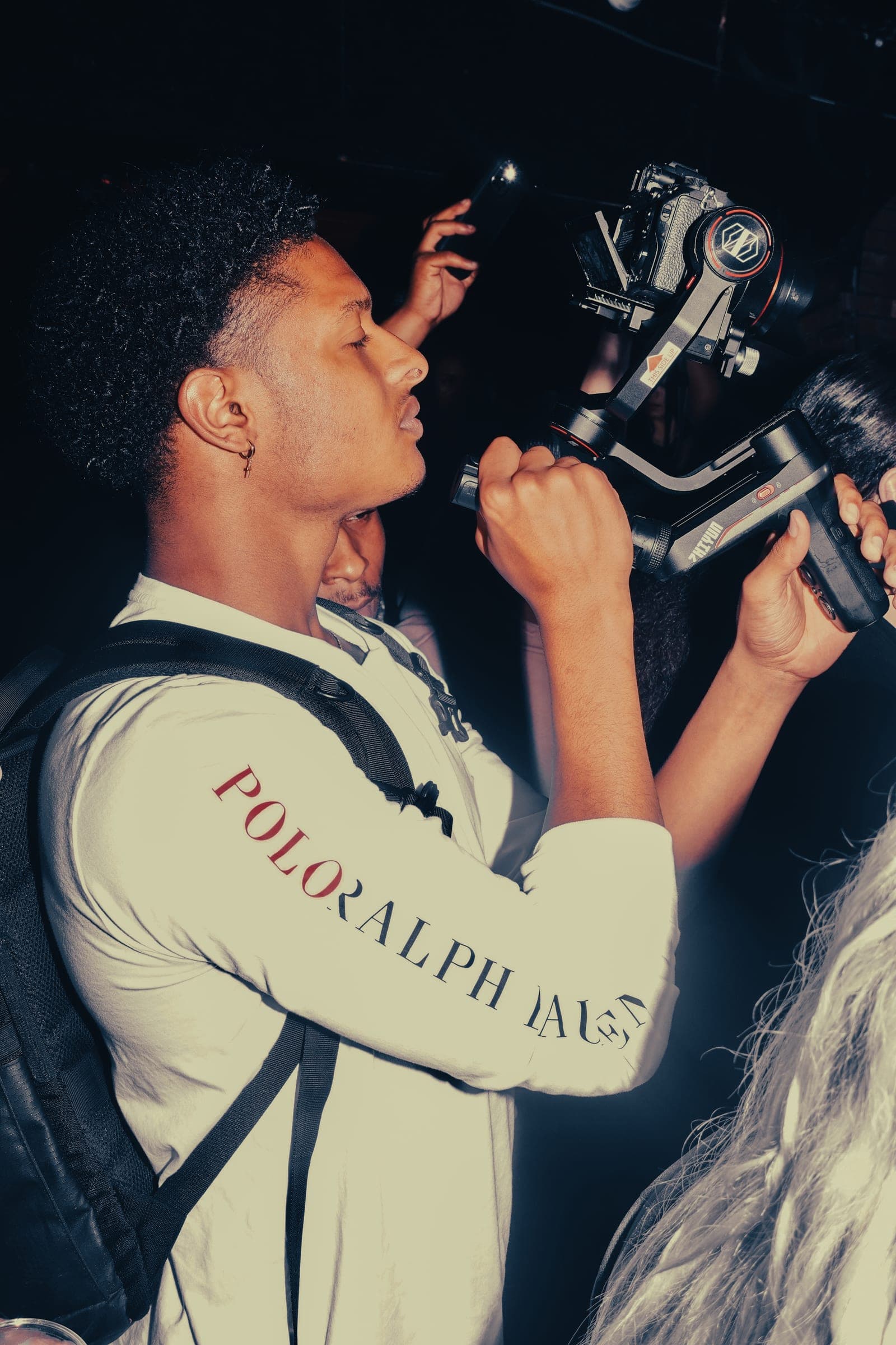 Alijah filming on a gimbal in a crowded room at night